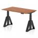 The picture is of a sleek and modern office desk. It features a dynamic sit stand function and can be adjusted to different heights. The top is made of rich walnut wood, while the legs are black. The desk also has a unique piste foot design.