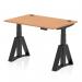 The photograph shows a sleek and modern Dynamic Sit Stand and Height Adjustable Desk, measuring 1200 x 800mm. The desk features an oak top with cable ports, supported by a black leg with a Piste foot for added stability and style.