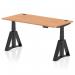 The image shows a sleek and modern office desk with an oak top and black legs. The desk is 1600 x 800mm and features height adjustability, with visible cable ports for organization. The unique piste foot adds a touch of style and functionality.