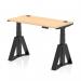 The photograph shows a spacious air 1200 x 600mm office desk in maple top with black legs. It features a dynamic sit stand and height adjustable design with cable ports and a piste foot for added functionality.