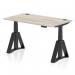 This picture shows a dynamic sit stand and height adjustable desk with a grey oak top measuring 1400 x 800mm. The desk has cable ports for organization and a black leg with a piste foot for stability.