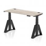 This picture features a sleek and modern office desk, measuring 1400 x 600mm, with a grey oak top and black legs. The desk is fully height adjustable and comes with cable ports and a piste foot for added convenience. Ideal for creating a dynamic and ergonomic workspace.