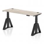 This image shows a sleek, modern office desk with a grey oak top and black legs. It features a dynamic sit stand design and is adjustable in height from 600mm to 1600mm. The desk also has convenient cable ports and a unique piste foot for added stability.