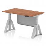 This picture features a sleek and modern 1400 x 800mm height adjustable office desk with a walnut top and silver leg. The desk also has a silver steel modesty panel and piste foot for added stability. The dynamic sit stand and height adjustable design allows for versatility in any office space.