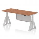 This photo shows a dynamic sit stand and height adjustable desk with an air modesty panel. The desk has a 1800 x 800mm walnut top, silver legs, and a silver steel modesty panel. The piste foot adds stability and style.