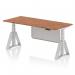 This photo shows a dynamic sit stand and height adjustable desk with an air modesty panel. The desk has a 1800 x 800mm walnut top, silver legs, and a silver steel modesty panel. The piste foot adds stability and style.