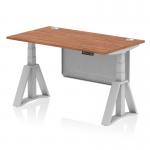 This picture shows a sleek and modern office desk with a walnut top and silver legs. The desk is adjustable in height and features cable ports for organization. A silver steel modesty panel and piste foot add to the functionality of the desk.
