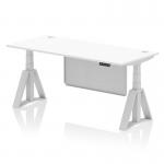 This photo shows a sleek and modern dynamic sit-stand and height adjustable desk. The desk features a white top with cable ports, silver legs, and a silver steel modesty panel. The piste foot adds a stylish touch to this 1800 x 800mm office desk.