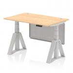 This photograph features a modern, sleek office desk with a maple top and silver legs. It has cable ports for easy organization and a steel modesty panel with a piste foot for added stability. The desk is height adjustable, allowing for a dynamic sit-stand work style.