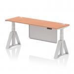The photo shows a sleek and modern office desk with a beech wood top and silver legs. It features adjustable height and a steel modesty panel with cable ports for a clean and organized workspace. The addition of a piste foot adds stability to this dynamic sit stand desk.
