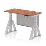 This photograph showcases a dynamic sit stand and height adjustable desk with a walnut top and silver legs. It includes cable ports for easy organization and a silver steel modesty panel. The piste foot adds stability and style to the desk.