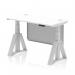This photograph features a modern office desk with a white top, silver legs, and a silver steel modesty panel. The desk is 1200 x 600mm and is height adjustable with a piste foot for added support. It also includes cable ports for easy organization and a sleek, dynamic design.
