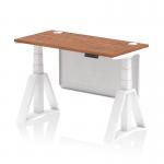 This photograph features a dynamic sit stand and height adjustable office desk with a walnut top and white legs. The desk measures 1200 x 600mm and includes cable ports and a white steel modesty panel with piste foot.