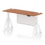 This image shows a modern, functional office desk with a walnut top and white steel legs. The desk is 1600 x 600mm in size and features a dynamic sit stand function as well as height adjustability. There are cable ports for organization and a white steel modesty panel with a piste foot for support.