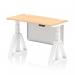 The photograph features a sleek and modern Dynamic Sit Stand and Height Adjustable Desk. The desk is 1200 x 600mm and boasts a stylish maple top with convenient cable ports. The white leg and sturdy steel modesty panel add a touch of elegance, while the Piste Foot ensures stability for a comfortable work experience.
