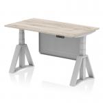 This image showcases a sleek grey oak top desk with a silver leg and steel modesty panel. It is height adjustable and features a piste foot for added stability. The desk also boasts a dynamic sit stand function, making it versatile for any office setting.