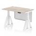 The picture shows a sleek and modern office desk with a grey oak top and white steel legs. The desk is 1200 x 800mm in size and features adjustable height options. It also includes convenient cable ports and a white steel modesty panel with a piste foot. The design allows for a dynamic sit-stand work style.