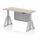 This picture features a sleek and modern Dynamic Sit Stand and Height Adjustable Desk. The desk measures 1400 x 600mm and has a Grey Oak top with cable ports. The legs are a striking silver color, as well as the steel modesty panel. The desk also includes a Piste Foot for extra stability.