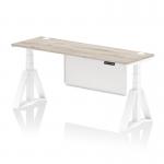 This photo features a dynamic sit stand and height adjustable desk, measuring 1800 x 600mm. The desk has a grey oak top and white steel legs with a white modesty panel. It also includes cable ports and a piste foot for added functionality.