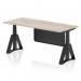 The photo shows a dynamic sit stand and height adjustable desk in an office setting. The desk has a grey oak top and black leg, with a black steel modesty panel and piste foot. The size of the desk is 1800 x 800mm. This versatile desk allows you to easily switch between sitting and standing positions while working.