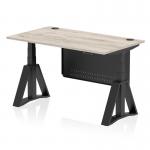 This picture features a sleek and modern height adjustable desk with a grey oak top, black steel legs and a matching modesty panel. The desk also includes cable ports and a piste foot for added stability. It offers both a standing and sitting option for a comfortable and dynamic work experience.