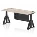 The photo shows a modern and versatile office desk with a grey oak top and black metal legs. It features a height adjustable design and cable ports for convenience. A sleek black steel modesty panel and piste foot add a touch of style to the dynamic sit stand desk.