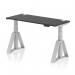 This photograph displays a modern and versatile office desk with adjustable height options. The sleek black top is contrasted with silver legs and features cable ports for organization. The unique Piste Foot adds support and style to the overall design.