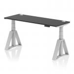 This photo shows a sleek and modern Dynamic Sit Stand and Height Adjustable Desk. The desk has a black top, silver legs with a piste foot, and cable ports for organization. Its dimensions are 1600 x 600mm.