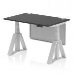The picture shows a sleek Dynamic Sit Stand and Height Adjustable Desk with a 1200 x 800mm black top and silver legs. The desk also features cable ports, a silver steel modesty panel, and a piste foot for added stability. This desk is perfect for any modern office space.