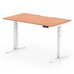 The photograph shows a dynamic sit stand and height adjustable desk, measuring 1400 x 800mm. It features a scalloped edge and a beech top with white legs. The desk is in a modern office setting, with natural light and green plants in the background. The desk can be seen in both sitting and standing positions, and the height adjustment mechanism is clearly visible.