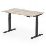 This picture shows a modern office desk with a grey oak top and black legs. It has a scalloped edge and can easily be adjusted to sit or stand at a height of 1400mm by 800mm. This ergonomic design promotes movement and adaptability, allowing for a more dynamic and comfortable workspace.