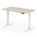 The photo shows a modern and sleek office desk with a grey oak top and white legs. The unique scalloped edge adds a touch of style. It is designed to be adjustable in both height and sitting positions, making it a functional choice for any workspace.