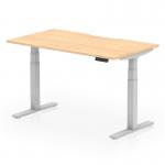 The picture shows a dynamic sit-stand desk with a scalloped edge maple top and silver legs. It is 1400 x 800mm in size and features height adjustability for a versatile office setup. The sleek design and modern features make it a great addition to any workspace.