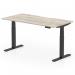 This photo is a close-up of a sleek grey oak top with a scalloped edge placed on top of a dynamic sit stand and height adjustable desk. The black legs provide a sturdy base for the desk, which measures 1600 x 800mm.