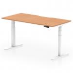 This photo features a modern office desk with a sleek oak top and white legs. Its scalloped edge adds a touch of elegance. Designed for versatility, it is both height adjustable and can easily switch between sitting and standing positions.