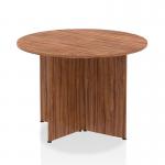 The photograph is a close-up of a round table with a rich walnut top and unique arrowhead legs. The table exudes a dynamic and modern vibe, making it a striking addition to any space.