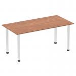 The picture shows a sleek and modern Dynamic Tables Impulse 1600mm straight table. The tabletop is made of dark walnut and is supported by shiny chrome post legs. Its clean lines and bold design make it a perfect addition to any office space.