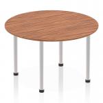 The photo features a sleek and modern Dynamic Round Tables Impulse 1200mm Round Table. The table top is a rich walnut color, while the post leg is made of brushed aluminium. Set against a clean white background, this table exudes style and functionality.