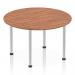 The photo features a sleek and modern Dynamic Round Tables Impulse 1200mm Round Table. The table top is a rich walnut color, while the post leg is made of brushed aluminium. Set against a clean white background, this table exudes style and functionality.