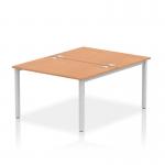 This photo features a dynamic bench desking setup with two workstation spaces, each with a silver frame and oak desk surface. The sleek, modern design and sturdy construction make it perfect for any office environment.