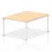 Two people are seen sitting at a white framed bench desk, which is designed with a dynamic bench desking impulse. The office bench desk features a maple color and is able to accommodate two persons comfortably.