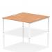 The image shows a modern and versatile work setup, with two people sitting at a sleek white bench desk with a sturdy oak top. The dynamic design of the bench desking allows for collaborative and efficient work, while the white frame adds a touch of elegance to the office space.