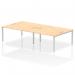 This photograph shows a modern office space with a dynamic set of four silver-framed bench desks from the Impulse Bench B2B collection. The desks are arranged in a 1600 design and feature a sleek maple finish. The clean and functional design is perfect for a professional work environment.
