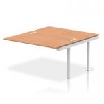 The photograph showcases a stylish and modern bench desking set-up, featuring the Dynamic Bench Impulse Bench with 1400mm B2B Ext Kit. The silver frame and oak desk surface create a professional and sleek look for any office space.