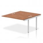 The photo shows a sleek and modern office bench desk with a silver frame and a walnut top. The desk is equipped with a dynamic bench desking impulse bench B2B ext kit and measures 1400 in length. It exudes professionalism and functionality.