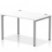 This photo showcases a dynamic bench desking set-up, featuring a sleek silver frame and a single row of desks in a spacious office setting. The clean, white finish of the desks adds a modern touch while the open layout allows for collaborative work.