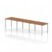 This photo captures a sleek and modern office setup with a single row of dynamic bench desking, featuring a silver frame and walnut desktop. Three people can comfortably work side by side on this spacious and functional desk.