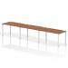 The photo shows a sleek and modern Dynamic Bench desking system. The Impulse bench, with a white frame and walnut top, can seat three people in a single row. It is perfect for creating a collaborative and efficient workspace in any office setting.