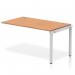 This photograph shows a sleek and modern office bench desk with a silver frame and oak top. The desk has a dynamic design and is versatile for use in various office settings. A single row extension kit allows for additional workspace. It exudes professionalism and functionality.