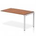 The picture shows a spacious, modern workplace setup with a dynamic bench desking system. The silver frame and walnut desk create a sleek and professional look, while the single row extension kit adds versatility to the layout. This bench desk is perfect for any office environment.